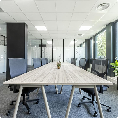 Salle de réunion lumineuse du Trigone B’Coworker à Angers, équipée d’une grande table et de chaises de bureau.