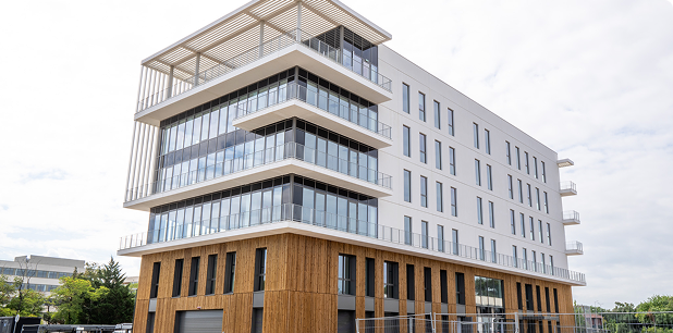 Vue extérieure du bâtiment A du SPI, livré par le Groupe FSDV à Sopra Steria, avec façades vitrées, bardage bois et volumes contemporains.
