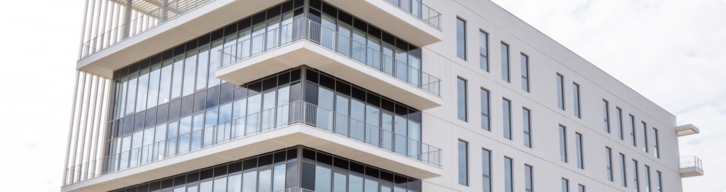 Détail de la façade vitrée du bâtiment A du SPI, avec balcons filants et architecture contemporaine.