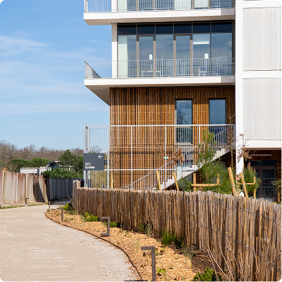 Entrée extérieure du bâtiment A du SPI, avec bardage bois, balcons et cheminement paysager.