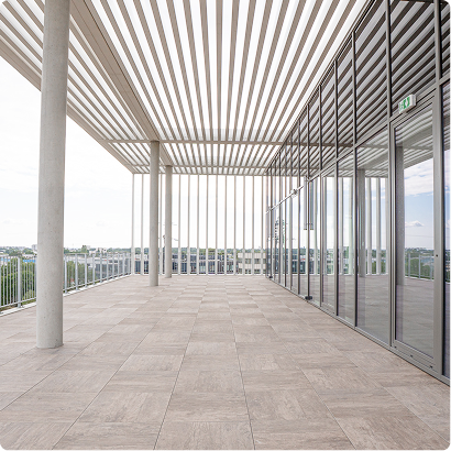 Terrasse couverte du bâtiment A du SPI, avec structure ajourée, larges baies vitrées et vue dégagée.