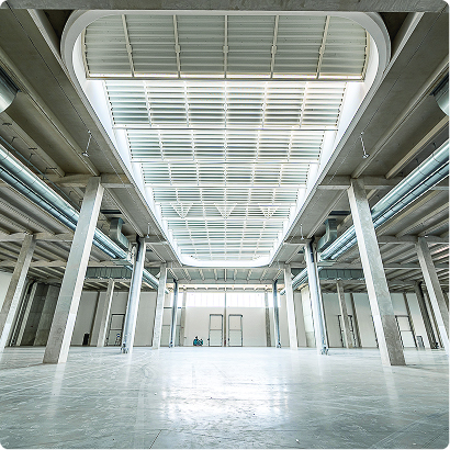 Grand espace intérieur de l’Imaginarium, avec structure apparente, colonnes, plafond technique et sol clair.