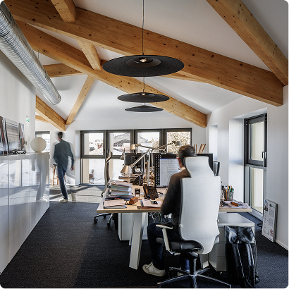 Espace de bureaux lumineux de BPM Architectes avec charpente apparente, postes de travail et grandes ouvertures.