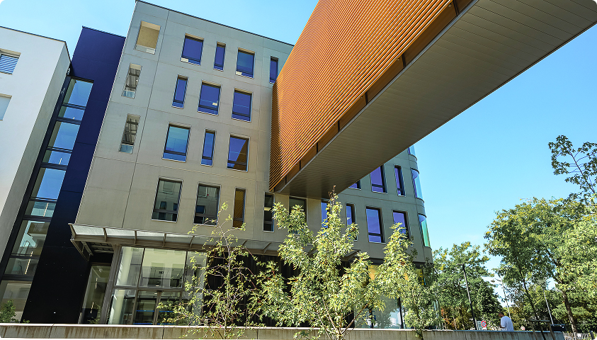 Vue extérieure du projet La Passerelle, projet de FSDV, avec bâtiment contemporain, passerelle orange, façades vitrées et espaces paysagers.