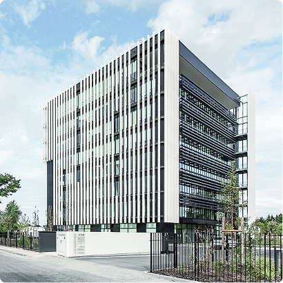 Vue extérieure de l’immeuble Le Bridge, projet de FSDV, avec façade contemporaine, brise-soleil verticaux et accès paysager.
