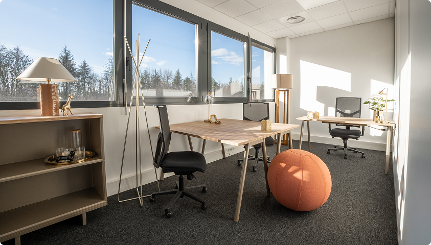 Bureau lumineux du centre B’Coworker à Lille, équipé de postes de travail, fauteuils et assise ronde colorée.