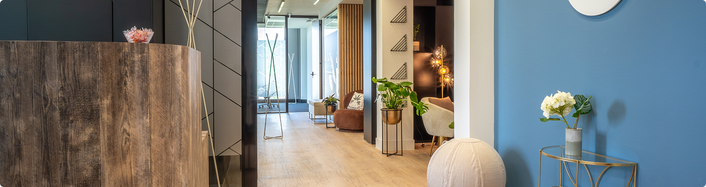 Vue panoramique de l’accueil du centre B’Coworker Lille Sud, avec comptoir, espace détente, décoration végétale et mur bleu.