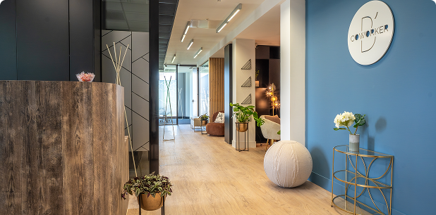 Accueil du centre B’Coworker Lille Sud, avec comptoir en bois, signalétique murale, décoration végétale et espace lounge.